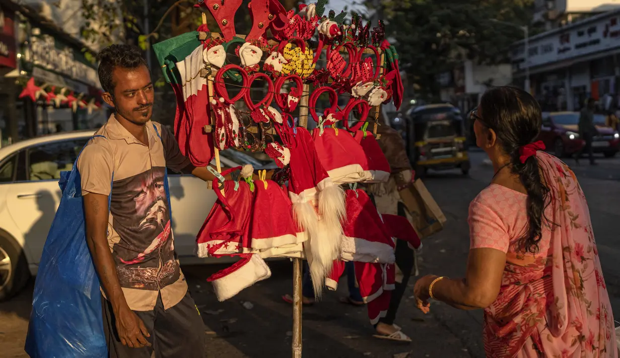 Seorang wanita berbelanja oleh-oleh Natal dari pedagang pinggir jalan di Mumbai, India, Selasa (20/12/2022). Jelang puncak perayaan Natal, warga Mumbai mulai ramai berburu ornamen dan aksesoris Natal untuk menyambut dan memeriahkan perayaan untuk umat kristiani tersebut. (AP Photo/Rafiq Maqbool)