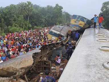 Orang-orang berkumpul di dekat gerbong kereta yang rusak parah setelah dua kereta yang melaju bertabrakan di distrik Brahmanbaria, 82 kilometer (51 mil) timur ibukota, Dhaka, Bangladesh, Selasa (12/11/2019). Sekitar 16 orang tewas dan 60 lainnya terluka akibat kecelakaan tersebut. (AP Photo)