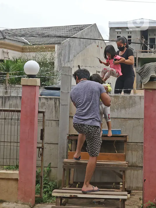 Warga memanjat tembok untuk memasuki rumahnya di kawasan Ciledug, Kota Tangerang, Banten, Senin (15/3/2021). Penutupan akses menuju rumah dan tempat usaha milik wargatersebut sejak 21 Februari 2021 karena permasalahan sengketa lahan. (Liputan6.com/Herman Zakharia)