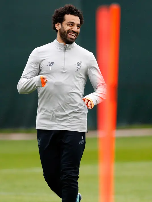 Penyerang Liverpool asal Mesir Mohamed Salah tersenyum saat melakukan pemanasan di kompleks pelatihan Melwood tim di Liverpool, Inggris barat laut, (23/4). Liverpool akan bertanding melawan wakil Italia, AS Roma di stadion Anfield. (AFP Photo/Paul Ellis)
