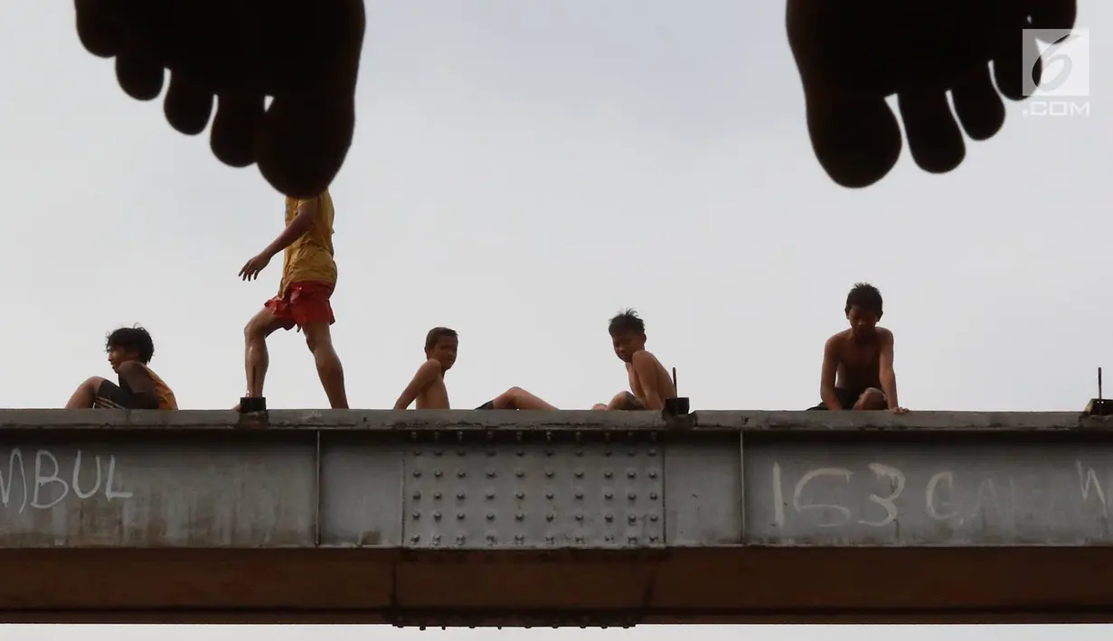 Anak-anak bersiap melompat ke Sungai Ciliwung yang meluap di kawasan Rawajati, Jakarta, Jumat (26/4). Tingginya volume debit air yang berasal dari Bogor tidak menyurutkan niat anak-anak itu untuk tetap berenang, meskipun berbahaya bagi keselamatan. (Liputan6.com/Immanuel Antonius)