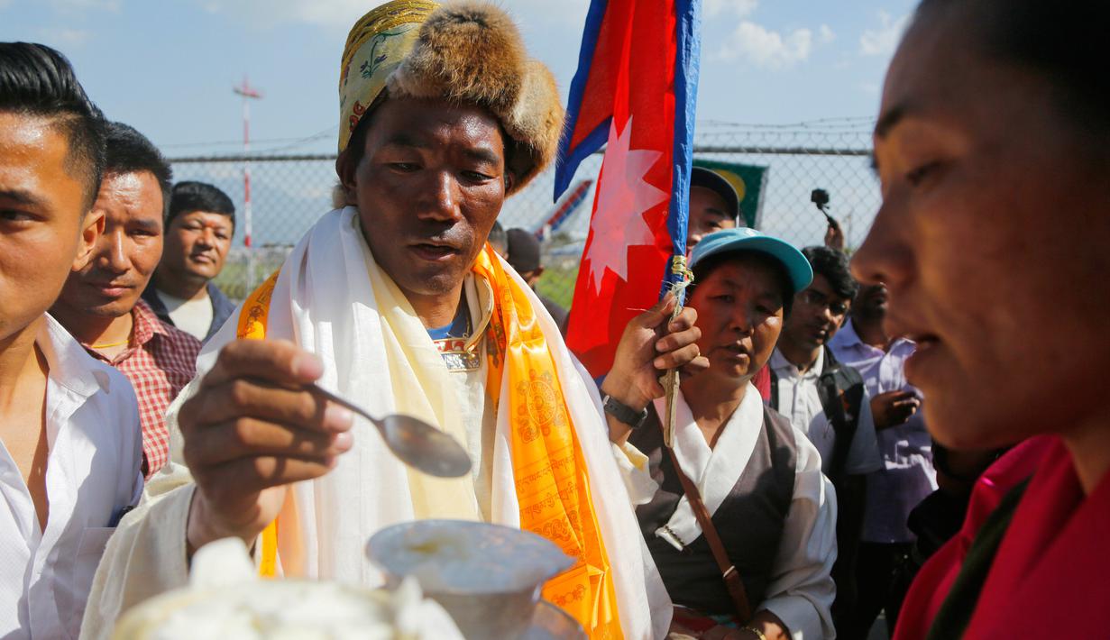 Pendaki asal Nepal, Kami Rita Sherpa disambut oleh istrinya di bandara di Kathmandu, Nepal, Sabtu (25/5/2019). Kami merupakan penduduk asli Desa Thame yang terletak di dekat Gunung Everest. (AP Photo/Niranjan Shrestha)