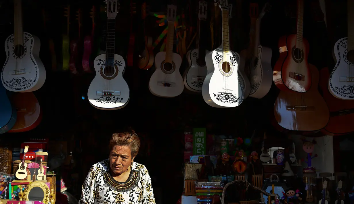Seorang wanita menjual replika gitar dari film "Coco" di kiosnya di Paracho, Meksiko (8/1). Kerena kepopuleran film animasi Coco pengrajin di Meksiko dibanjiri pesanan gitar yang mirip di film tersebut. (AFP Photo/ Ronaldo Schemidt)