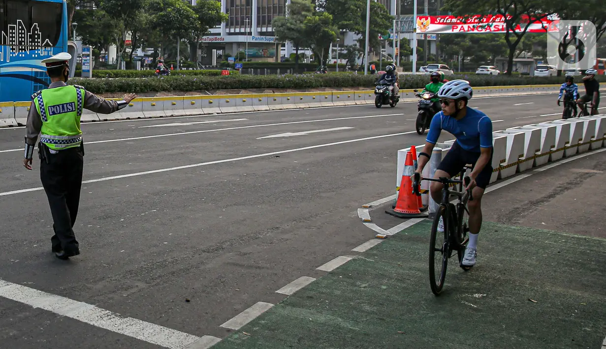 Polisi menghalau pesepeda yang berada di luar jalur di kawasan Sudirman-Thamrin, Jakarta Pusat, Rabu (2/6/2021). Sepeda road bike diperbolehkan untuk melintas di Jalan Sudirman-Thamrin pada hari kerja Senin-Jumat, namun dibatasi dari pukul 05.00-06.30 WIB. (Liputan6.com/Faizal Fanani)