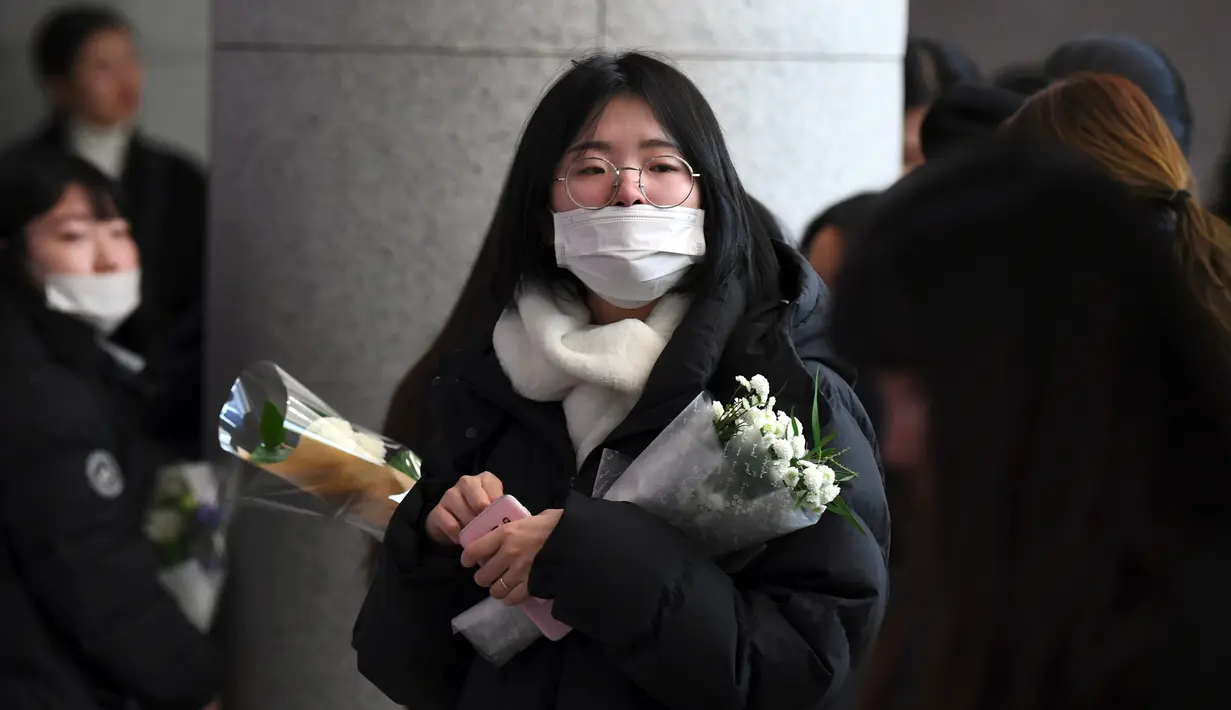 Seorang fans datang membawa bunga untuk memberikan penghormatan kepada Jonghyun SHINee di rumah duka Seoul Asan Hospital, Selasa (19/12). Kepergian Jonghyun SHINee ini menjadi pukulan mendalam bagi keluarga, sahabat, dan penggemar. (JUNG Yeon-Je / AFP)
