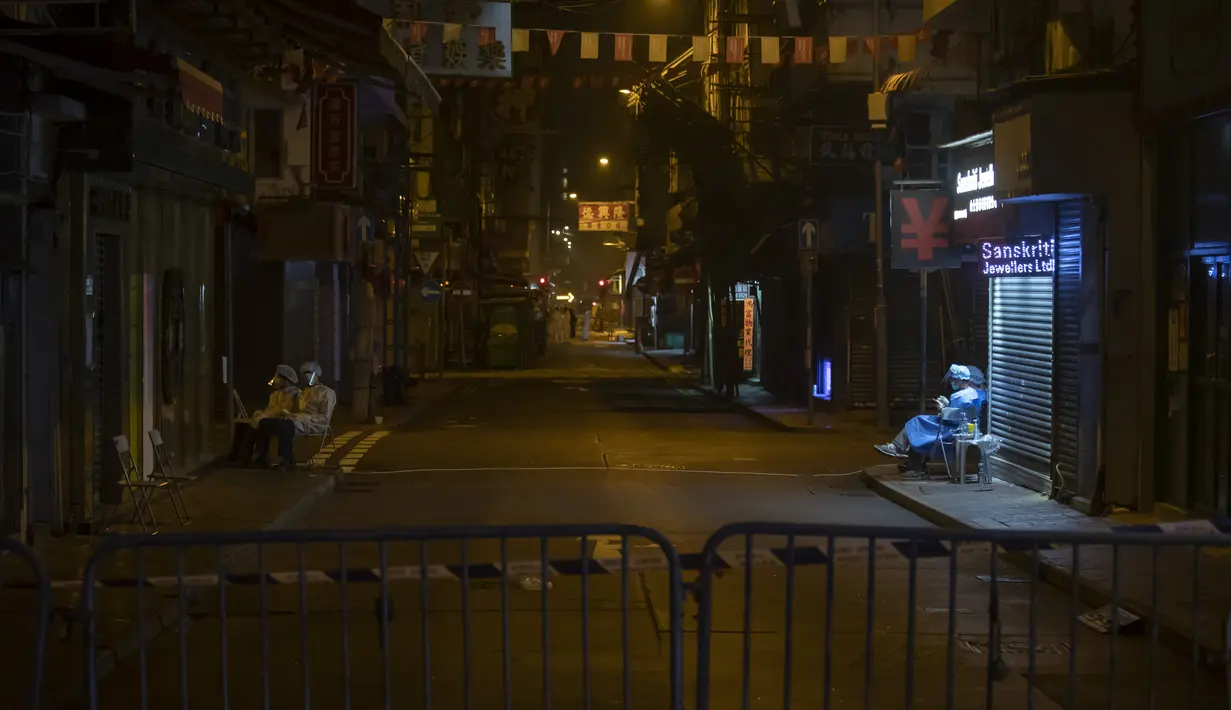 Sejumlah petugas kesehatan mengenakan APD berjaga di area tertutup di distrik Jordan, di Hong Kong, Minggu (24/1/2021). Lockdown diterapkan di distrik Jordan dan Sham Shui Po yang yang mencakup sebagian kecil kota, tapi padat penduduk di Semenanjung Kowloon. (AP Photo/ Kin Cheung)
