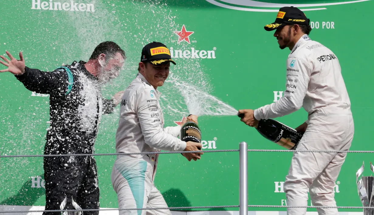 Pembalap tim Mercedes, Lewis Hamilton dan Nico Rosberg menyemprotkan sampanye ke arah direktur teknis Mercedes, Paddy Lowe saat merayakan kemenangan di balapan F1 Grand Prix Meksiko, Meksiko (30/10). (Reuters/Henry Romero)