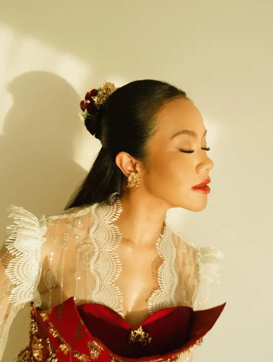 Pada foto ini, Yura tampil dalam balutan bustier merah berhias payet emas yang dipadukan dengan kebaya transparan berpotongan cape.  [@yurayunita].