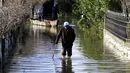 Seorang pria tua berjalan di jalan yang banjir di Desa Obot, sekitar 100 kilometer (60 mil) barat laut Tirana, Albania, Senin (11/1/2021). Pihak berwenang telah mengevakuasi banyak warga menyusul banjir yang merendam ribuan hektare (acre) kawasan di Albania. (AP Photo/Hektor Pustina)