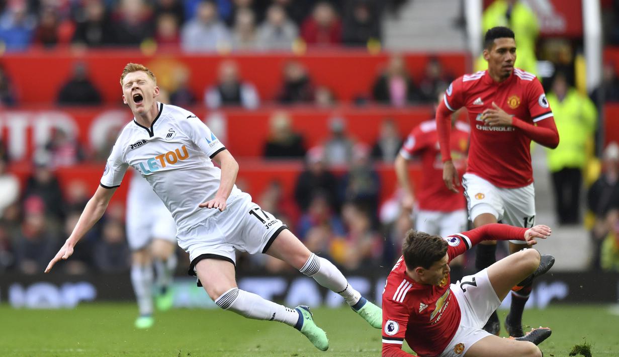 Pemain Swansea City, Sam Clucas (kiri) kesakitan saat di jegal pemain Manchester United, Victor Lindelof pada laga Premier League di Old Trafford, (31/3/2018).  Manchester United menang 2-0. (Anthony Devlin/PA via AP)