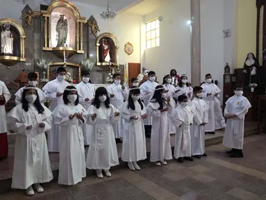 Anak-anak memakai masker pelindung selama upacara Perjamuan Kudus pertama di tengah pandemi virus corona baru di gereja Katolik Nuestra Senora de la Merced di Lima, Peru, Jumat (3/12/2021). (AP Photo/Martin Mejia)