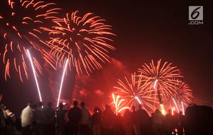 Pengunjung menyaksikan pesta kembang api saat malam Tahun Baru 2019 di Pantai Lagoon, Ancol, Jakarta, Selasa (1/1). Ancol menyajikan pesta kembang api musikal sepanjang 600 meter di bibir pantai dalam menyambut Tahun Baru 2019. (Merdeka.com/Iqbal Nugoho)
