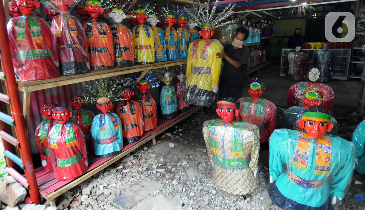 Seorang pria membawa ondel-ondel di Rumah Produksi Ondel-Ondel Jakarta, Setu Babakan, Jakarta Selatan, Minggu (19/9/2021). Setelah stagnan selama dua tahun akibat pandemi COVID-19, produksi dan penjualan ondel-ondel pasca PPKM Level 3 mengalami kenaikan hingga 20 persen. (merdeka.com/Arie Basuki)
