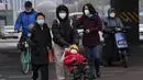 Seorang anak dengan masker didorong menyeberang jalan di Beijing, China, Jumat (2/12/2022). Lebih banyak kota melonggarkan pembatasan, memungkinkan pusat perbelanjaan, supermarket, dan bisnis lainnya dibuka kembali menyusul protes akhir pekan lalu di Shanghai dan daerah lain di mana beberapa orang menyerukan Presiden Xi Jinping untuk mengundurkan diri. (AP Photo/Ng Han Guan)