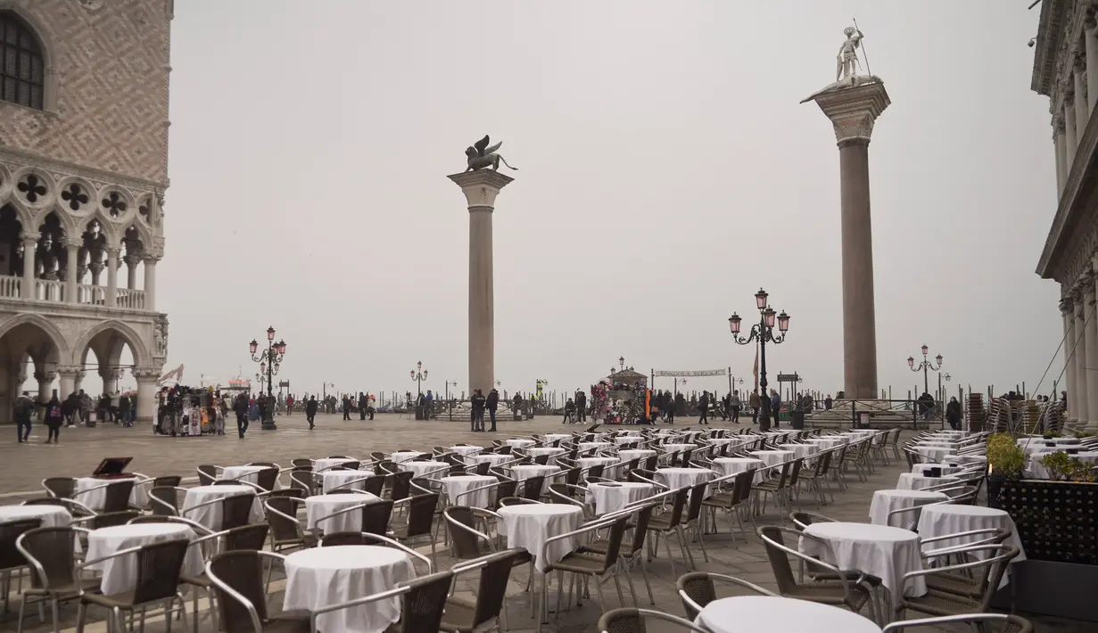 Meja-meja terlihat kosong di Alun-Alun St. Mark di Venesia, Italia, Selasa (25/2/2020). Pasien virus corona atau COVID-19 di Italia terus meningkat. (AP Photo/Renata Brito)