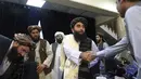 Juru bicara Taliban Zabihullah Mujahid, berjabat tangan dengan seorang wartawan setelah konferensi pers pertamanya, di Kabul, Afghanistan, pada Selasa (17/8/2021). Selama bertahun-tahun, Mujahid adalah sosok misterius yang mengeluarkan pernyataan atas nama para militan. (AP Photo/Rahmat Gul)