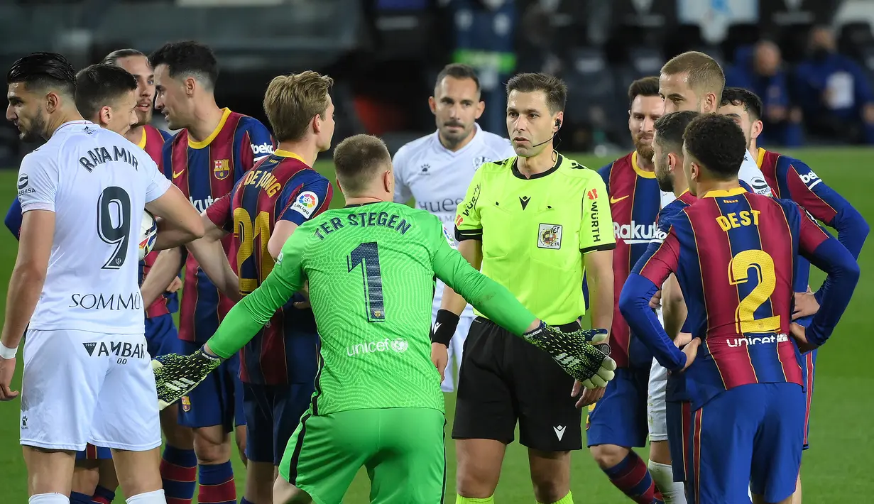 Para pemain Barcelona memprotes keputusan wasit Adrian Cordero Vega (tengah) yang memberikan hadiah penalti kepada SD Huesca dalam laga lanjutan Liga Spanyol 2020/2021 pekan ke-27 di Camp Nou Stadium, Barcelona, Senin (15/3/2021). Barcelona menang 4-1 atas SD Huesca. (AFP/Lluis Gene)
