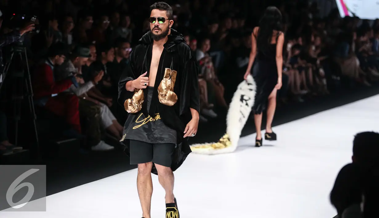 Seorang model pria membawa sarung tinju berjalan diatas catwalk dalam Jakarta Fashion Week 2017 di Jakarta, Minggu (23/10). Desainer Oxcel yang mengidolakan Muhammad Ali, menampilkan karyanya dengan elemen-elemen tinju. (Liputan6.com/Faizal Fanani)