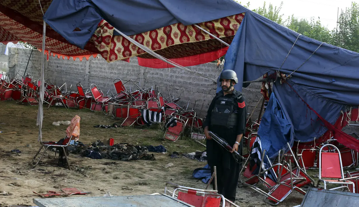 Seorang polisi Pakistan berjaga-jaga di lokasi serangan bom bunuh diri hari Minggu di distrik Bajur, Khyber Pakhtunkhwa, Pakistan, Senin, 31 Juli 2023. (AP Photo/Mohammad Sajjad)