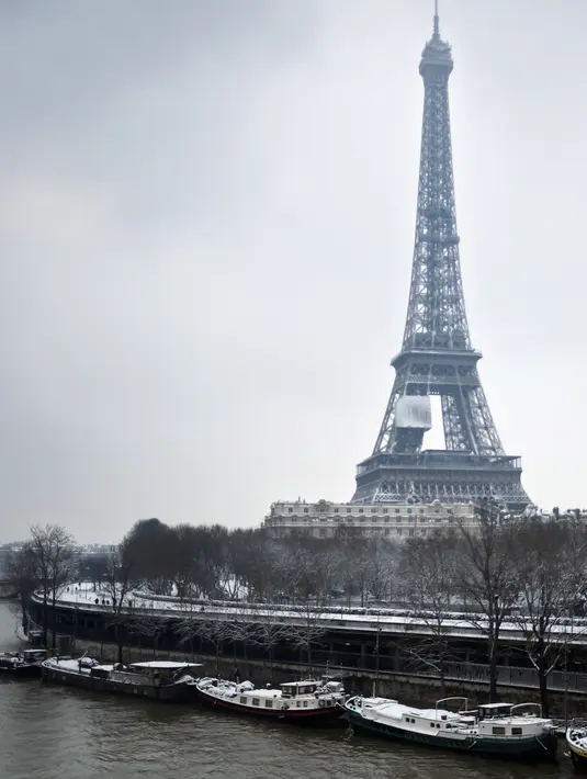 Suasana di dekat Menara Eiffel saat hujan salju di Paris, Prancis (7/2). Ratusan orang terpaksa meninggalkan mobil mereka untuk tidur di tempat penampungan darurat akibat cuaca ekstrem yang melanda. (AFP Photo/Stephane De Sakutin)