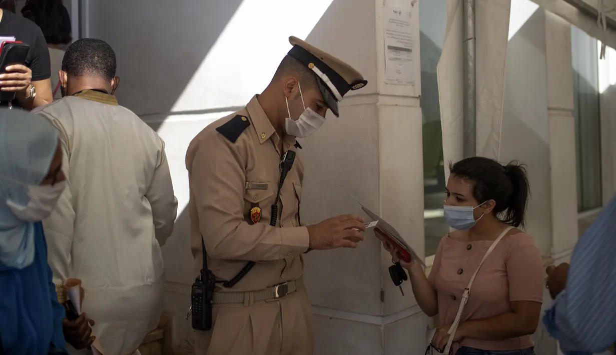 Petugas polisi memeriksa paspor vaksin seorang wanita sebelum diizinkan memasuki kantor pemerintah, di Rabat, Kamis (21/10/2021). Maroko mewajibkan paspor vaksin untuk mengakses kantor pemerintah, mal, pusat kebugaran dan area publik lain untuk mendorong kampanye vaksinasi (AP Photo/Mosa'ab Elshamy)