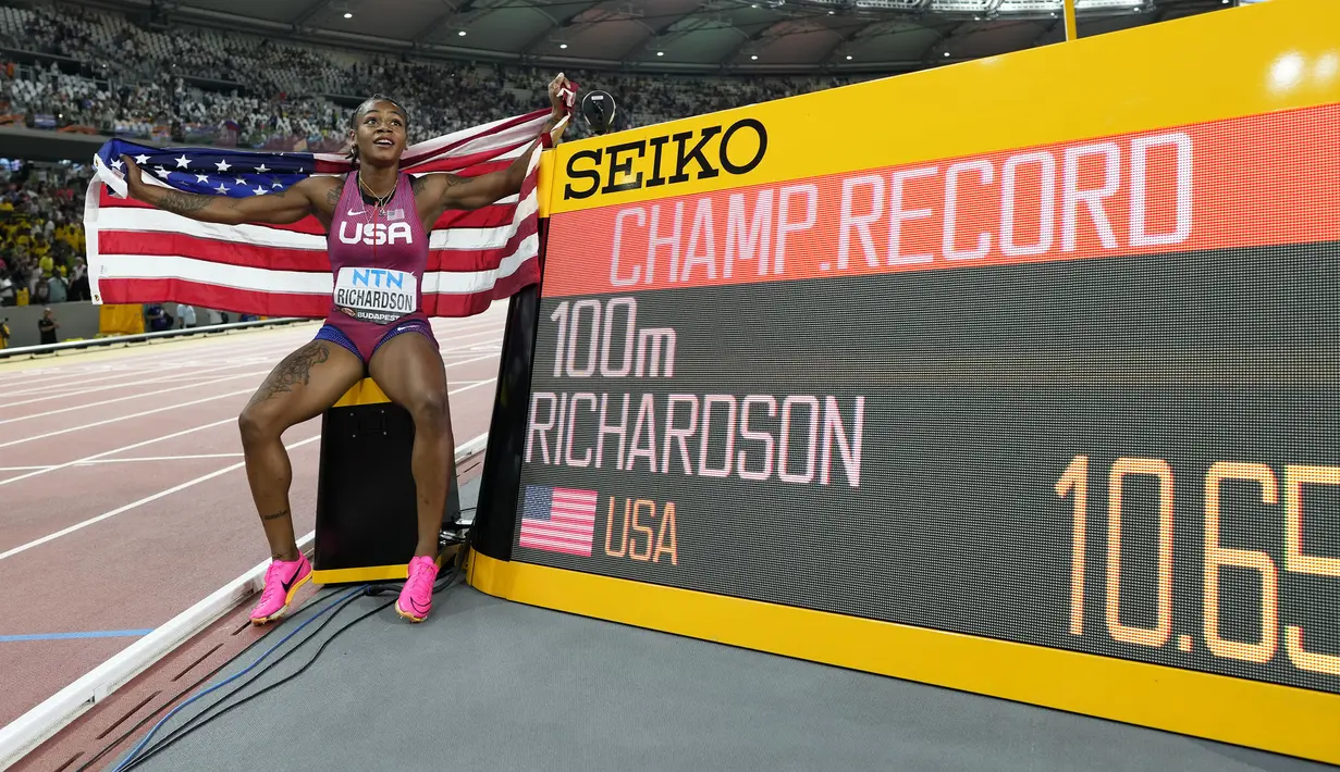 Pelari Amerika Serikat, Sha’Carri Richardson berfoto di samping papan catatan waktu setelah berhasil menorehkan rekor baru pada final 100 meter putri Kejuaraan Dunia Atletik 2023 di National Athletics Centre, Budapest, Hungaria, pada 22 Augustus 2023. (AP Photo/Bernat Armangue)