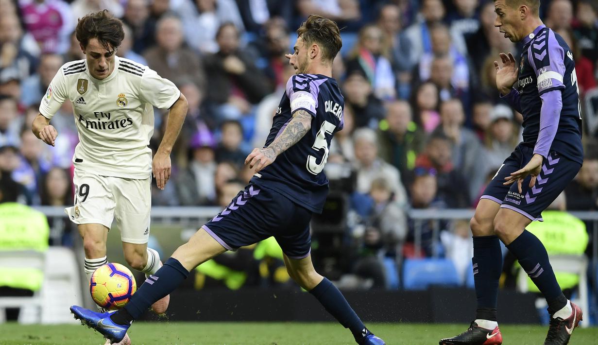 Bek Real Madrid, Alvaro Odriozola, berusaha melewati bek Real Valladolid, Fernando Calero, pada laga La Liga Spanyol di Stadion Santiago Bernabeu, Madrid, Sabtu (3/11). Madrid menang 2-0 atas Valladolid. (AFP/Javier Soriano)