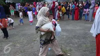 Seorang ibu membawa sembako usai mendapatkan paket sembako murah dari Indosiar di Joglo, Jakarta, Senin (13/6). Paket berisikan 5 kg beras, 2 liter minyak goreng, 1 kg gula pasir dan 1 kg tepung terigu dijual Rp 30 ribu‎. (Liputan6.com/Angga Yuniar)