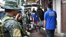 Personel polisi Filipina mengamati pekerja yang membawa jasad seorang napi yang tewas akibat kerusuhan di sebuah penjara di Filipina, Rabu (28/9). Selain menewaskan satu anggota geng narkoba, kerusuhan itu juga melukai tiga napi lainnya. (TED Aljibe/AFP)