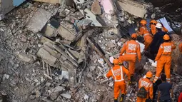 Petugas penyelamat mencari orang-orang di reruntuhan gedung apartemen berlantai lima yang runtuh di Mahad, India (25/8/2020). Polisi menyebut bangunan ini terdiri dari 47 flat. Sekitar 120 kilometer sebelah selatan Mumbai. (AFP Photo/Punit Paranjpe)