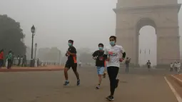 Sejumlah peserta yang mengikuti lomba New Delhi 10K berlari di depan India Gate yang diselimuti kabut tebal di New Delhi, India (31/10). Kabut asap ini diklaim sebagai kabut asap terparah yang dialami oleh New Delhi dalam 17 tahun. (AFP/Dominique Faget)