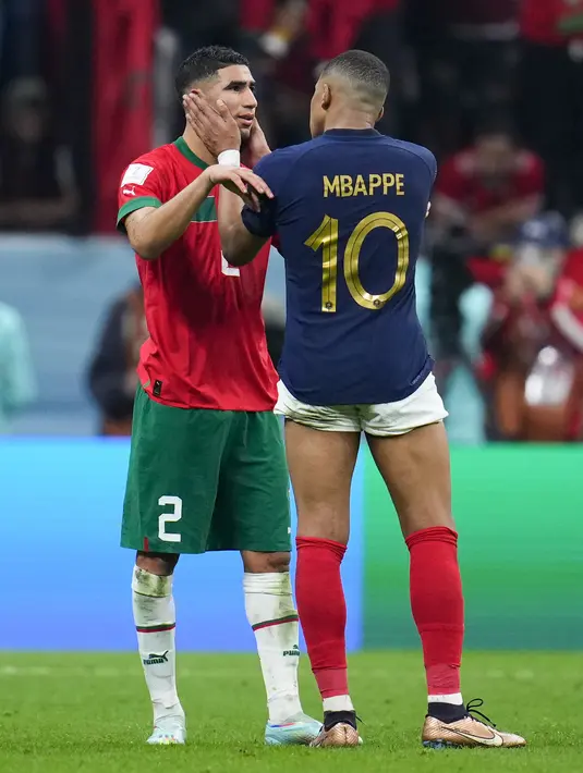 Penyerang #10 Prancis Kylian Mbappe menyapa bek Maroko #02 Achraf Hakimi setelah babak semifinal Piala Dunia 2022 di Al Bayt Stadium, Kamis (15/12/2022) dini hari WIB. Mbappe pun memeluk Hakimi bahkan keduanya juga tampak saling bertukar jersey. (AP Photo/Natacha Pisarenko)