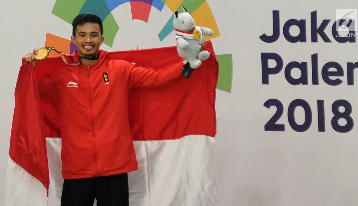 Pesilat Indonesia Abdul Malik mengangkat bendera Merah Putih usai menaklukkan Muhammad Faizul M Nasir asal Malaysia di final Kelas B Putra Asian Games 2018 di Jakarta, Senin (27/8). Abdul menang dan mendapatkan medali emas. (Merdeka.com/Arie Basuki)