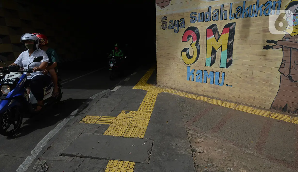 Sejumlah kendaraan melintas di depan mural anjuran kebiasan hidup baru dengan 3 M di Stasiun Cawang, Jakarta, Sabtu (26/12/2020). Pemerintah terus berupaya melakukan imbauan kepada warga untuk melaksanakan kebiasaan baru 3M guna memutus penyebaran virus corona (COVID-19). (merdeka.com/Imam Buhori)