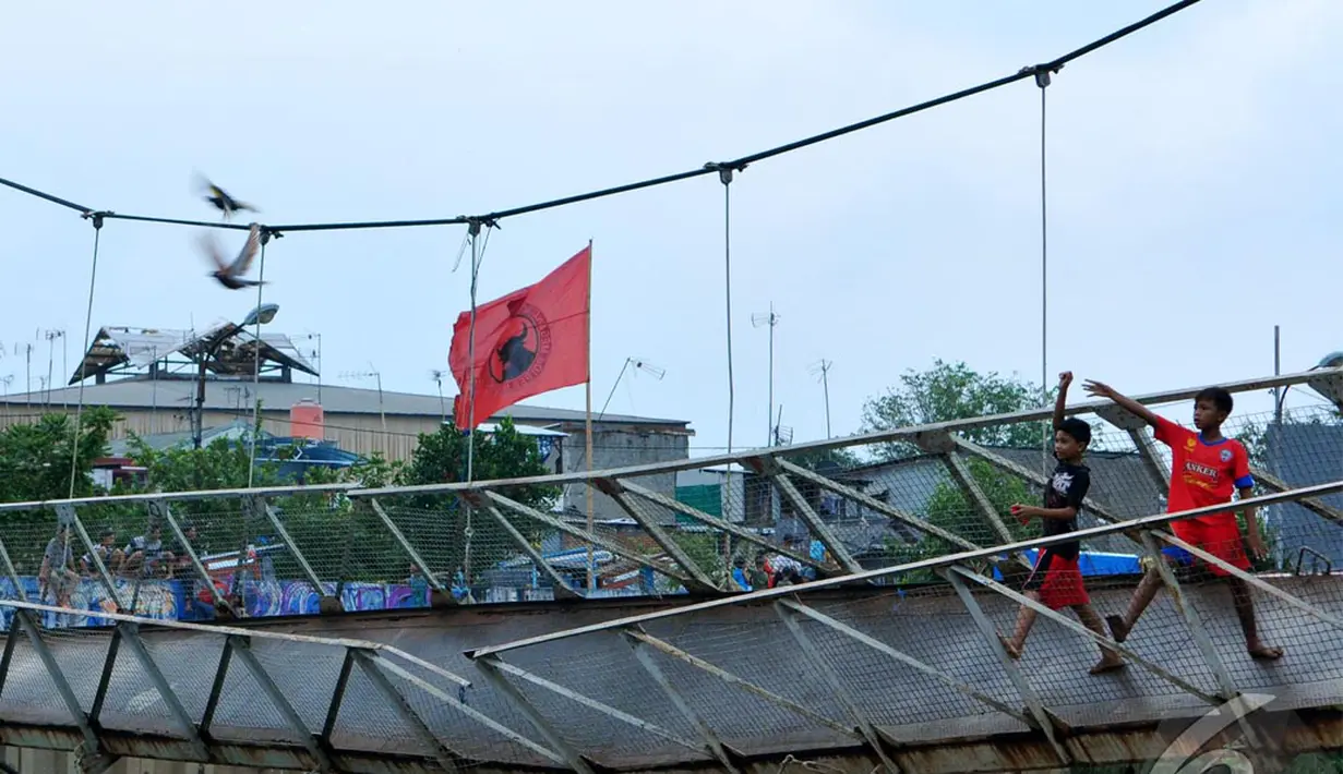 Para bocah ini bermain di Jembatan gantung yang menghubungkan Duri Pulo dan Grogol, Petamburan, Jakarta Barat. Meski rusak mereka tetap asyik bermain burung dara (Liputan6.com/Andrian M Tunay).