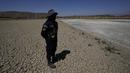 Seorang penjaga kota berdiri di dasar laguna Alalay yang retak dan kering di Cochabamba, Bolivia, Jumat (18/11/2022). Dua laguna, Coña Coña dan Alalay, berada pada level kritis karena kurangnya hujan, penumpukan bahan organik dan penguapan di tengah peningkatan suhu. (AP Photo/Juan Karita)