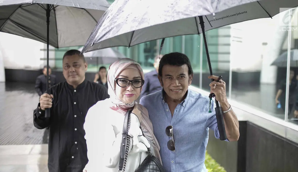 Rhoma Irama memayungi istrinya Ricca Rachim saat hadir dalam konferensi pers indosiar Ramadhan Penuh Berkah di Jakarta, Kamis (26/4). Pernikahan Rhoma Irama dan Ricca Rahim yang telah berusia 34 tahun ini jauh dari gosip. (Liputan6.com/Faizal Fanani)