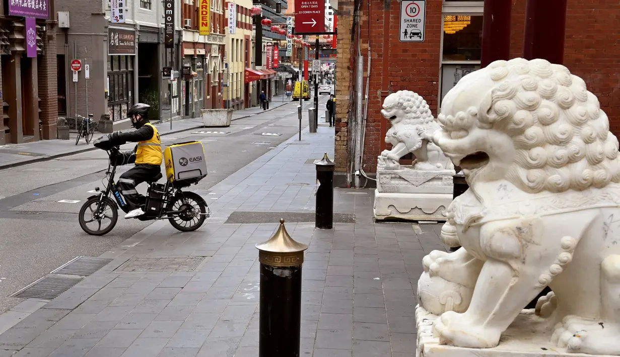 Seorang pengantar makanan menyusuri jalan yang sepi di Chinatown Melbourne, Australia, Selasa (19/10/2021). Melbourne bersiap mencabut aturan penguncian pekan ini setelah kota tersebut berada dalam enam lockdown selama 262 hari atau hampir sembilan bulan sejak Maret 2020. (William WEST/AFP)