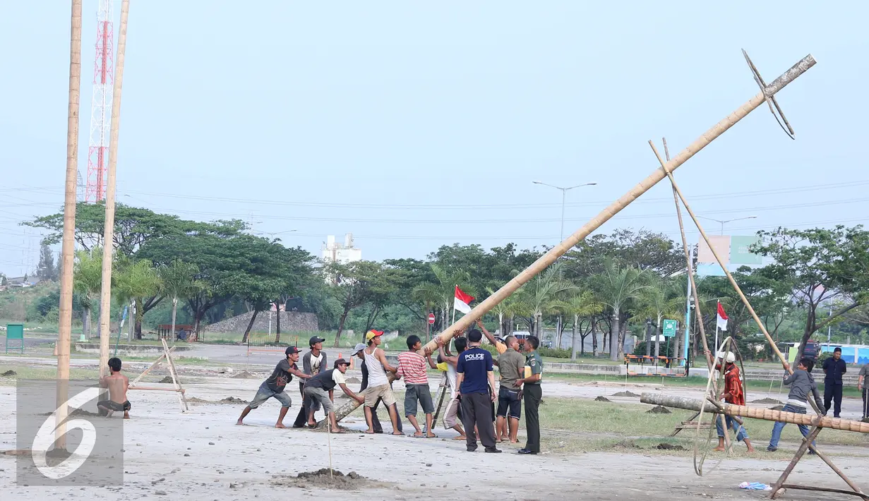 Pekerja mendirikan pohon pinang di Pantai Karnaval Ancol, Jakarta, Jumat (12/8). Taman Impian Ancol Jaya menyiapkan lomba panjat pinang kolosal dengan total pohon pinang mencapai 171 pohon. (Liputan6.com/Herman Zakharia)