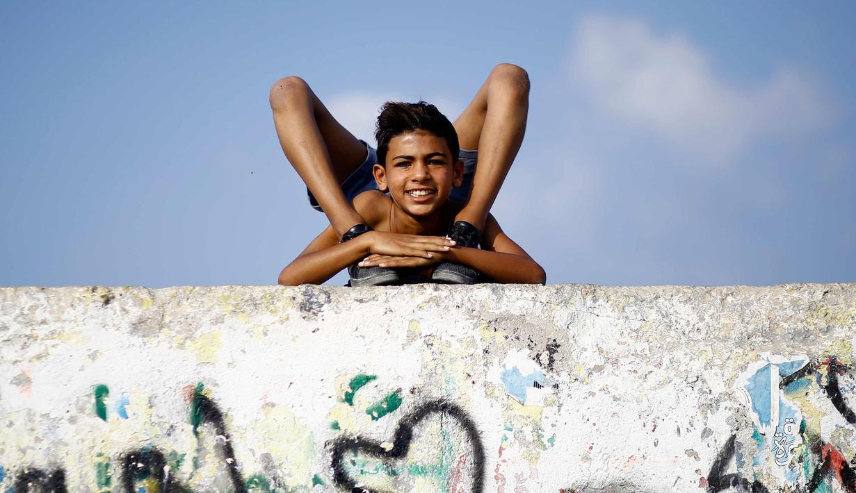 Yousef Al-Bahtini memperlihatkan keahlian akrobatiknya di pelabuhan Kota Gaza (20/9). Bocah Palestina ini siap memecahkan waktu tercepat rekor Guinness World Records dengan melakukan perjalanan 20 meter dalam kelenturan tubuh. (AFP Photo/Mohammed Abed)