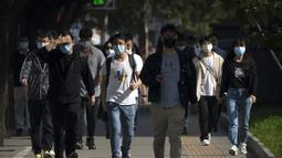 Penumpang yang mengenakan masker berjalan menuju kawasan pusat bisnis dari stasiun kereta bawah tanah yang belum ditutup di Beijing, Kamis (5/5/2022). Ibu kota China Beijing pada Kamis (5/5) mulai melonggarkan aturan karantina untuk kedatangan dari luar negeri. (AP Photo/Mark Schiefelbein)