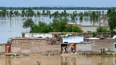Orang-orang berdiri di rumah mereka yang terendam banjir setelah hujan lebat di distrik Nowshera, Provinsi Khyber-Pakhtunkhwa, Pakistan pada tanggal 16 April 2024. (Abdul MAJEED/AFP)