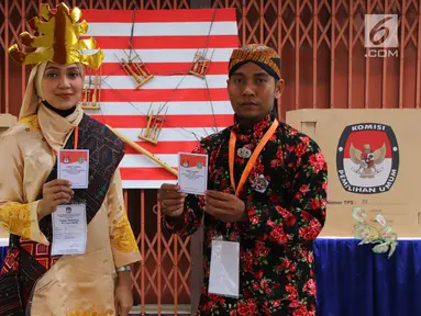 Petugas KPPS memegang surat suara pelaksanaan Pilkada Serentak 2018 di TPS XII Kelurahan Sei Mati, Kecamatan Medan Maimun, Rabu (27/6). Baju adat dari berbagai daerah dan suku tampak dikenakan oleh petugas TPS. (Liputan6.com/Reza Perdana)