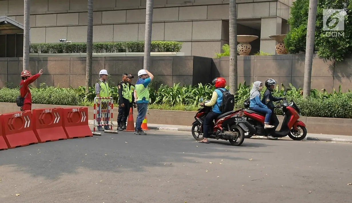 Petugas mengalihkan pengendara sepeda motor yang akan melintasi proyek pembangunan jalur kereta Light Rail Transit (LRT) di Jalan Setiabudi Tengah, Jakarta, Senin (17/6/2019). Jalan Setiabudi Tengah ditutup untuk memberi ruang terkait pengerjaan konstruksi jalur LRT. (Liputan6.com/Herman Zakharia)