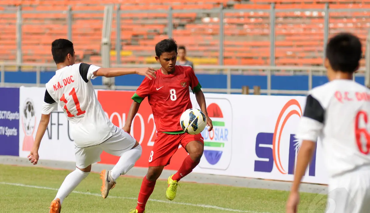 Gelandang timnas U-16 Indonesia, Amirulloh Ruslan (tengah) mencoba lolos dari kawalan Bui Anh Duc (Vietnam - kiri) saat berlaga di Stadion GBK Jakarta, (3/12). Timnas U-16 Indonesia unggul 3-2 atas Timnas U-16 Vietnam. (Liputan6.com/Helmi Fithriansya)
