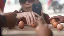 Warga mengambil gambar sambil mendirikan telur pada Perayaan Peh Cun di pantai Parangtritis, Yogyakarta, Kamis (9/6).  Ada fenomena menarik setiap perayaan Peh Cun. Sebutir telur dapat berdiri sendiri di atas bidang datar. (Liputan6.com/Boy Harjanto)