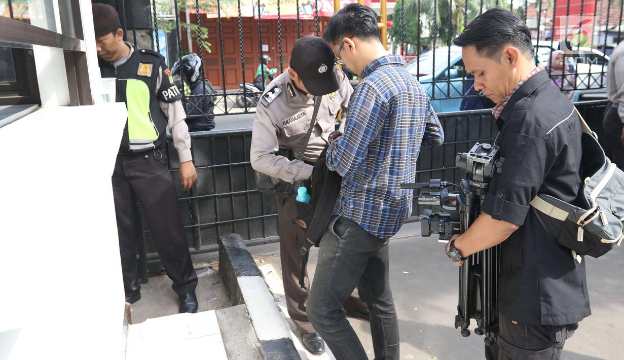 Personel kepolisian mengecek barang bawaan pengunjung yang masuk ke Pengadilan Negeri Jakarta Selatan, Jumat (22/6). Pengamanan berlapis diberlakukan pada sidang pembacaan vonis terdakwa terorisme Aman Abdurrahman. (Liputan6.com/Angga Yuniar)
