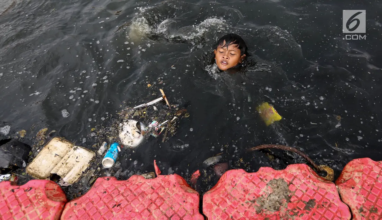 Seorang anak berenang di antara sampah di Kanal Banjir Barat (KBB), Petamburan, Jakarta, Senin (12/8/2019). Surutnya debit air KBB akibat musim kemarau dimanfaatkan anak-anak untuk bermain sambil mencari ikan. (Liputan6.com/Fery Pradolo)