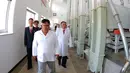 Pemimpin Korea Utara Kim Jong-un (tengah) melihat proses produksi ransum militer saat mengunjungi Pabrik No. 525 di Korea Utara, Rabu (25/7). (STRINGER/AFP/KCNA VIA KNS)