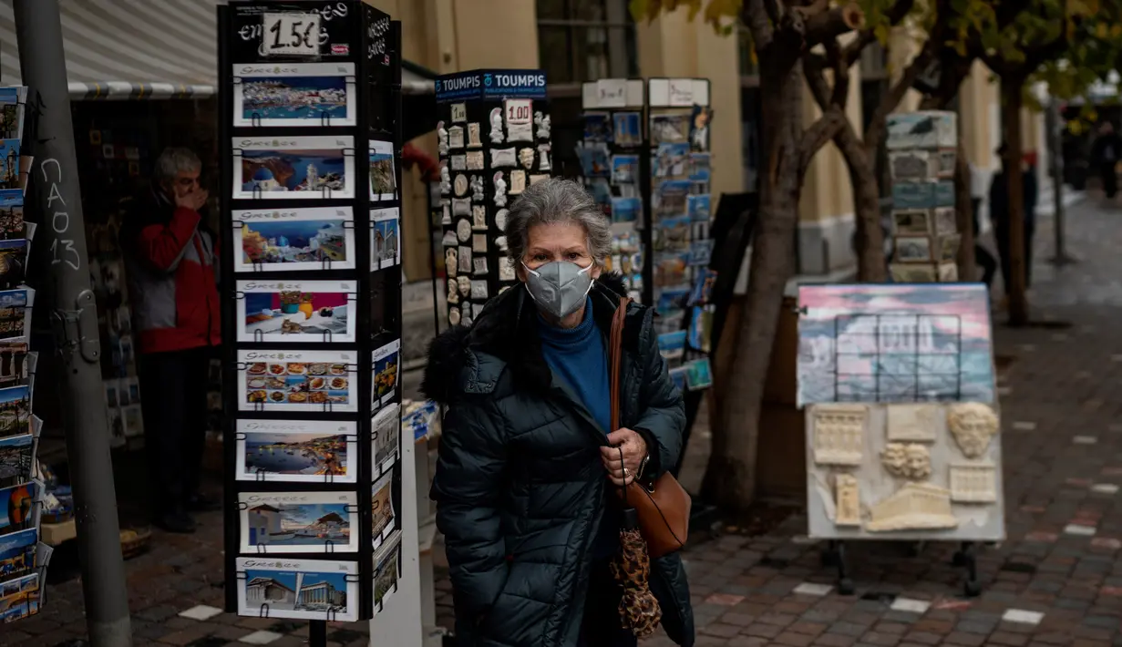 Seorang perempuan dengan masker berjalan di dekat Monastiraki square, pusat kota Athena, Yunani, Rabu (29/12/2021). WHO memperingatkan Organisasi Kesehatan Dunia (WHO) memperingatkan lonjakan kasus Covid-19 varian Omicron dapat menyebabkan fasilitas kesehatan kewalahan. (Angelos Tzortzinis/AFP)